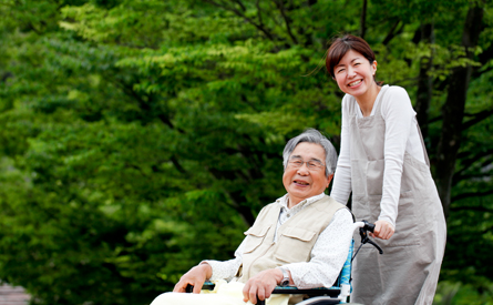 Japanese older man in wheelchair pushed by a Japanese woman